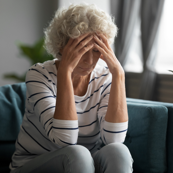 donna di mezza età che si tocca la testa con entrambe le mani